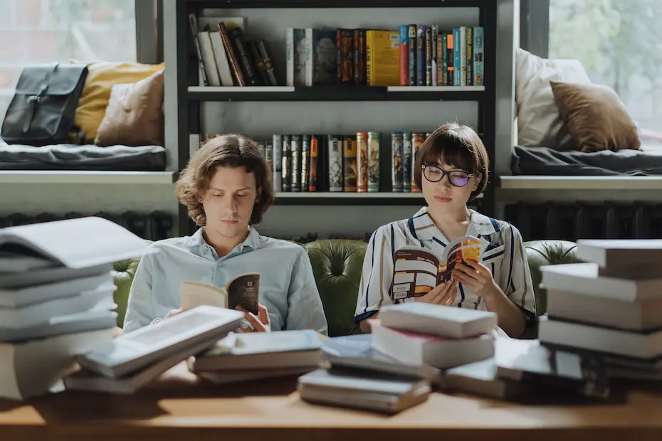 A couple reading books in a library.