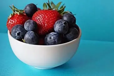 A bowl of straberries and blueberries.